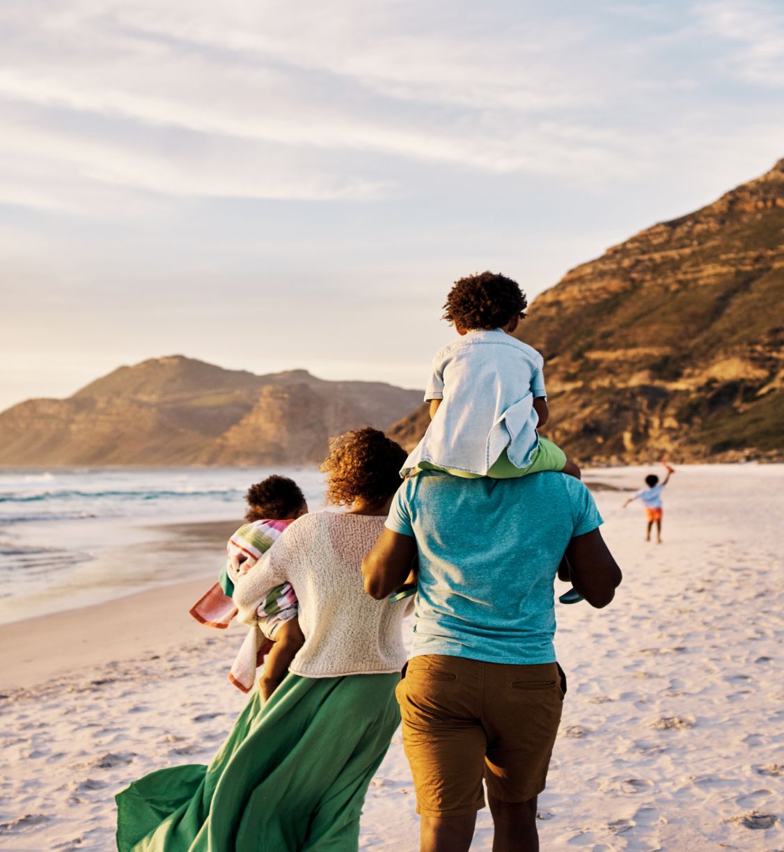 A young couple walking on the beach with their kids.