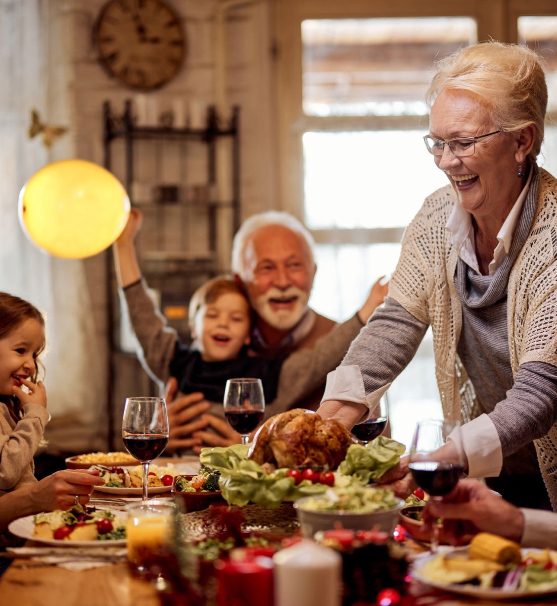 A older woman placing a cooked turkey on the table for family dinner.