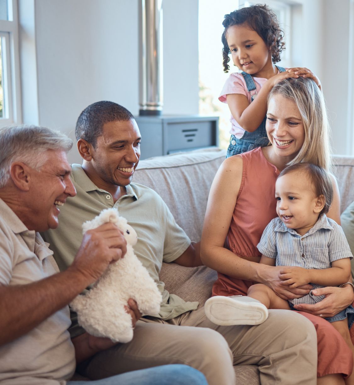 A multigenerational family sitting and laughing together on a couch.