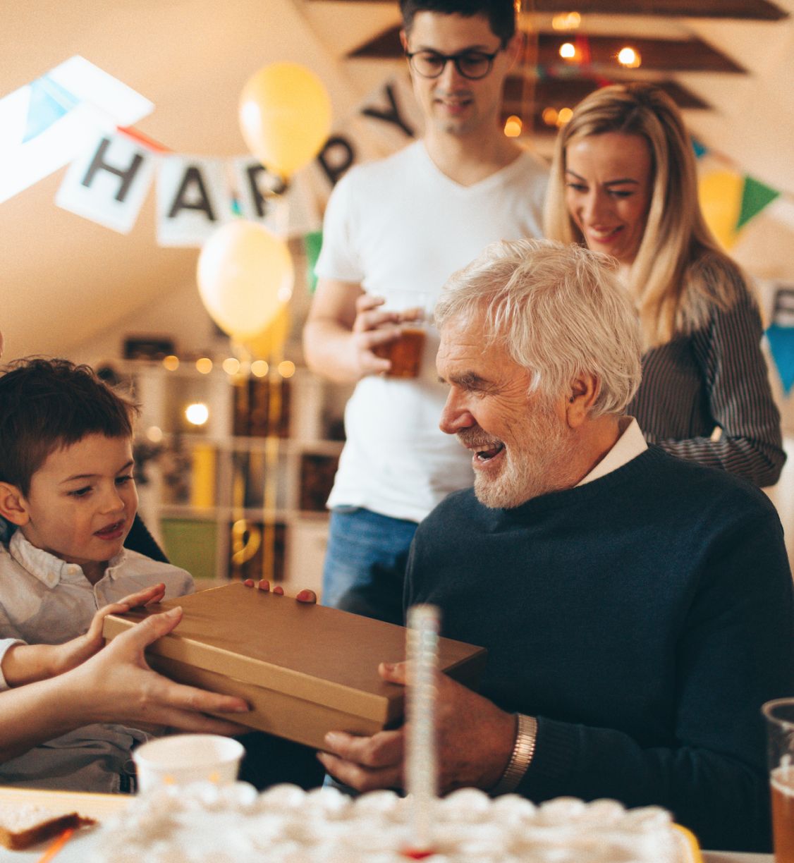 A little boy giving his grandfather a present on his birthday.